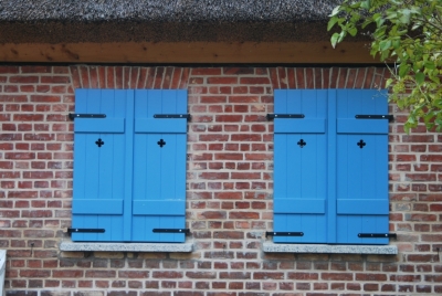 Blaue Brettläden mit schwarzen Klappladenbeschläge